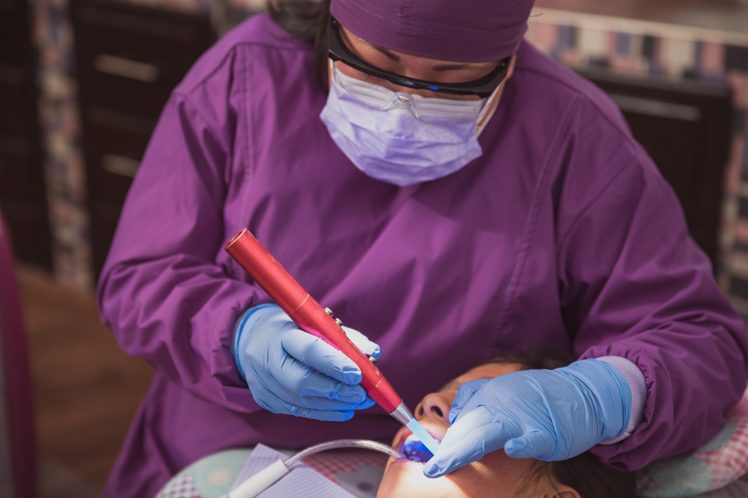 A female dentist performing dental treatment on a young girl.